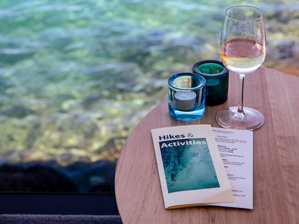 a glass of drink and hikes & activities flyer on the table by the water