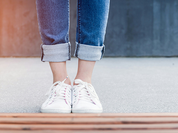 person in rolled up jeans and white sneakers