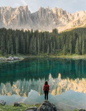 a woman standing at Lago di Carezza in Dolomites, Italy