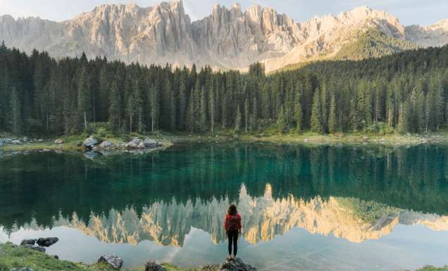 a woman standing at Lago di Carezza in Dolomites, Italy