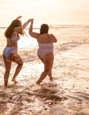 Young woman friends walking on the beach