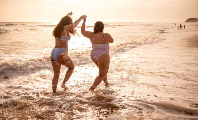 Young woman friends walking on the beach