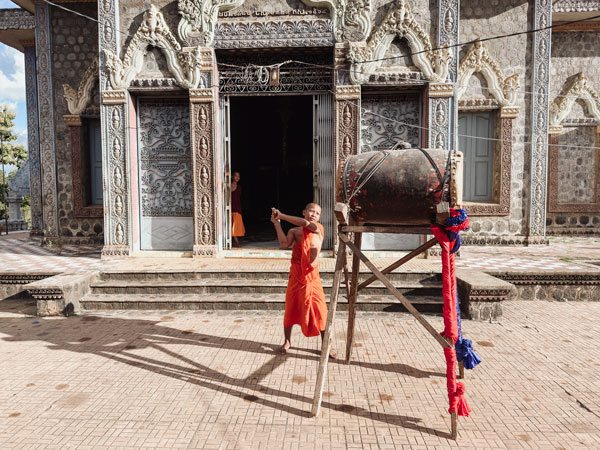 a young monk beating a drum at Phnom Pros