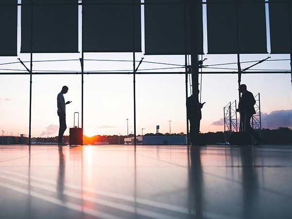 sillhouettes of people on their phones in airport