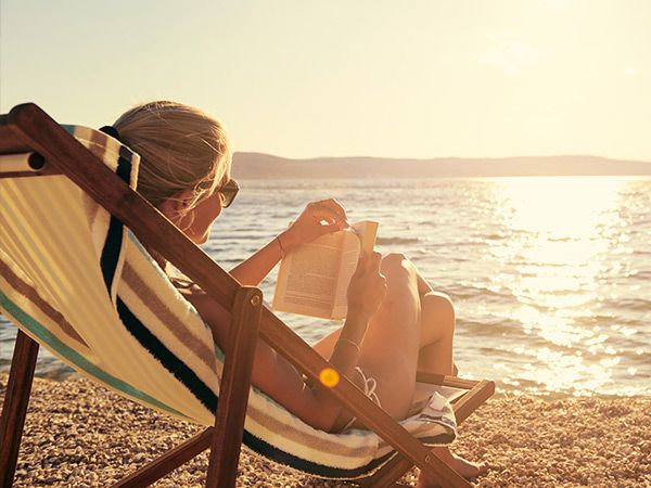 woman reading on the beach at sunset