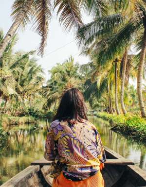 A young woman kayaks through the backwaters of Monroe Island in Kollam District, Kerala, South India.