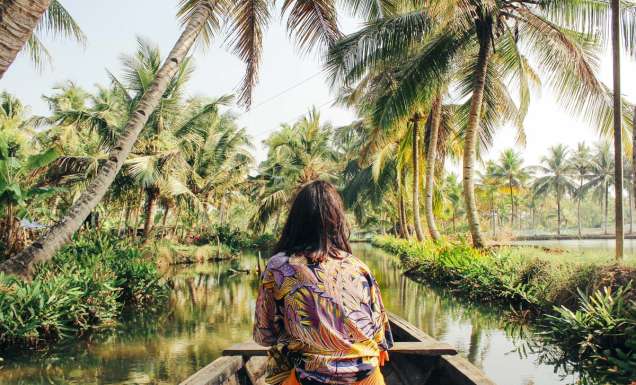 A young woman kayaks through the backwaters of Monroe Island in Kollam District, Kerala, South India.