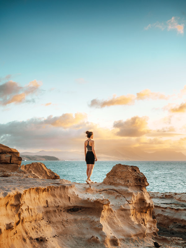 Woman standing on a cliff overlooking spectacular sunset 