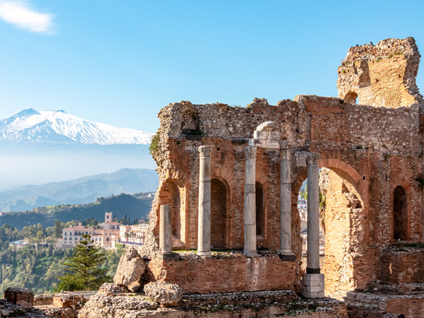 the snow-capped Mount Etna as seen from the ancient Greek theatre of Taormina, Italy