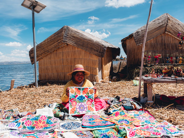 a woman sitting with textile art on display at Lake Titicaca