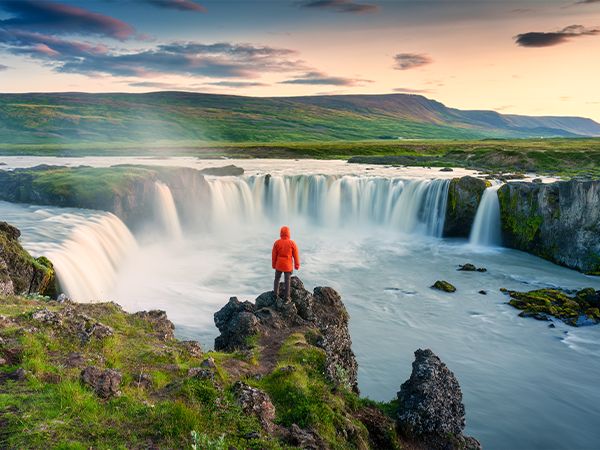 Godafoss waterfall flowing with colorful sunset