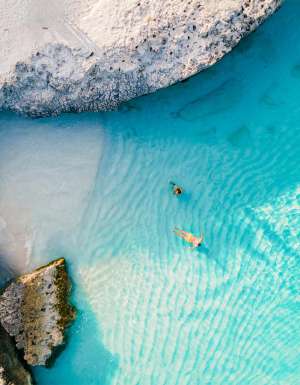 a couple of men and women on the beach of Tres Trap Aruba Caribbean Island. Tres Trapi Bay is popular with locals for snorkeling and diving in the turqouse colored ocean