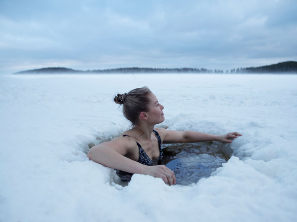 Woman swimming in the ice after a sauna in Finland