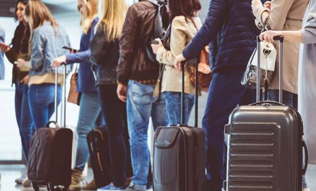 People lining up with carry-on baggage to board a flight