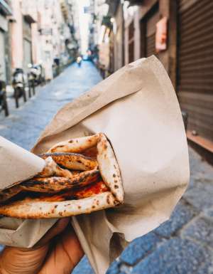 Point of view of a man eating a typical "Pizza a portafoglio" in Naples, Italy