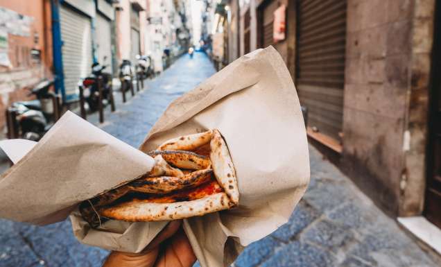 Point of view of a man eating a typical "Pizza a portafoglio" in Naples, Italy