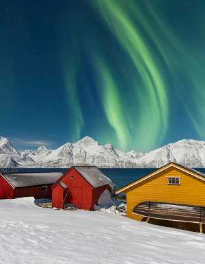 Traditional fisherman cottages in the snowy landscape under northern lights (aurora borealis), Lyngen Alps, Troms, Nord-Norge, Norway, Scandinavia