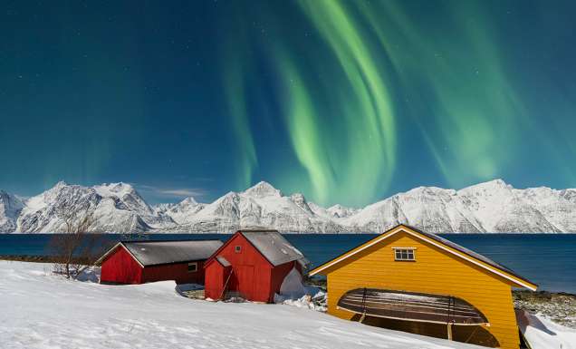 Traditional fisherman cottages in the snowy landscape under northern lights (aurora borealis), Lyngen Alps, Troms, Nord-Norge, Norway, Scandinavia