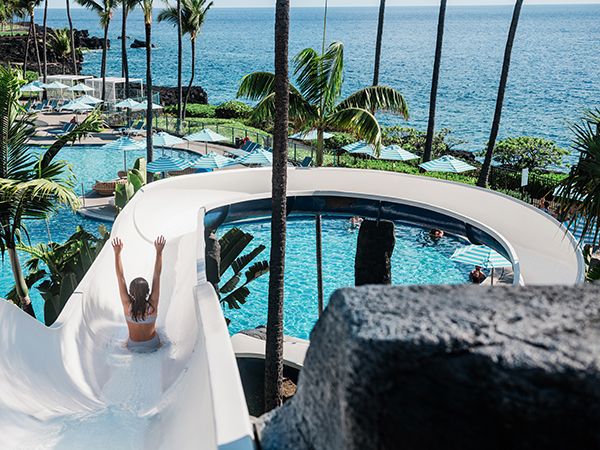 A woman enjoying a pool slide with the stunning sea as her backdrop.