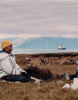 Local woman sits in the grasslands of Gjoa Haven / Uqsuqtuuq