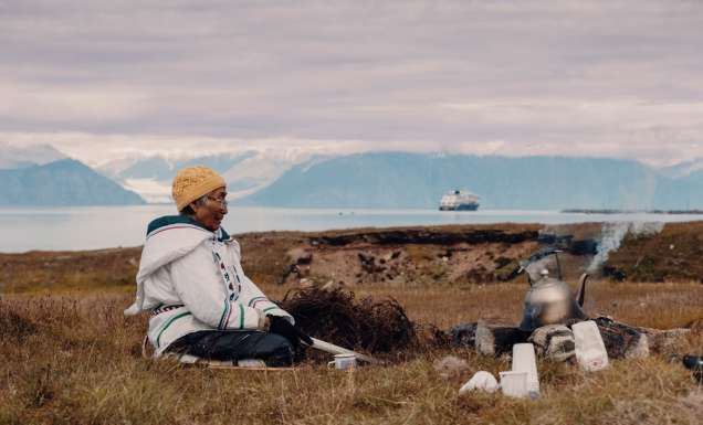 Local woman sits in the grasslands of Gjoa Haven / Uqsuqtuuq