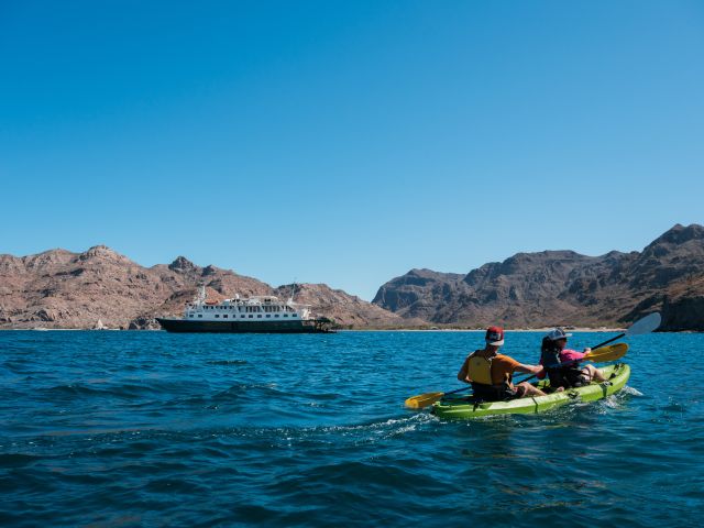 Uncruise guests kyaking near cruise ship