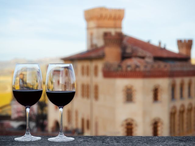 Two glasses of Barolo wine on a windowsill with the castle of Barolo (Piedmont, Italy) blurred on the background
