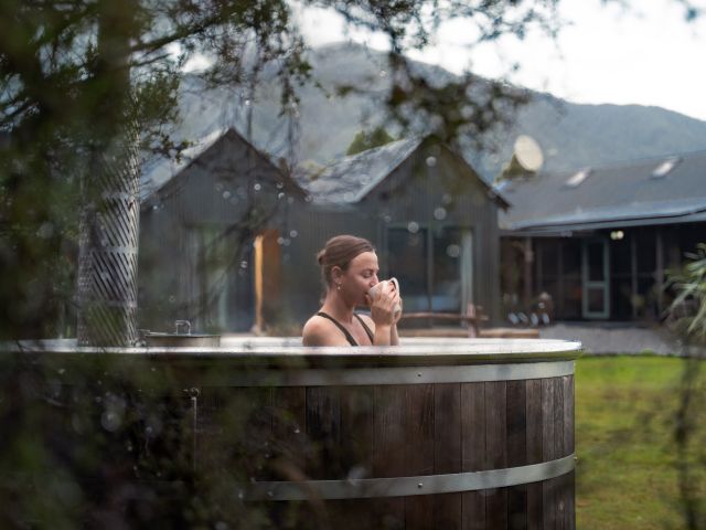 woman drinking tea in outdoor hot tub at Waitai Lodge