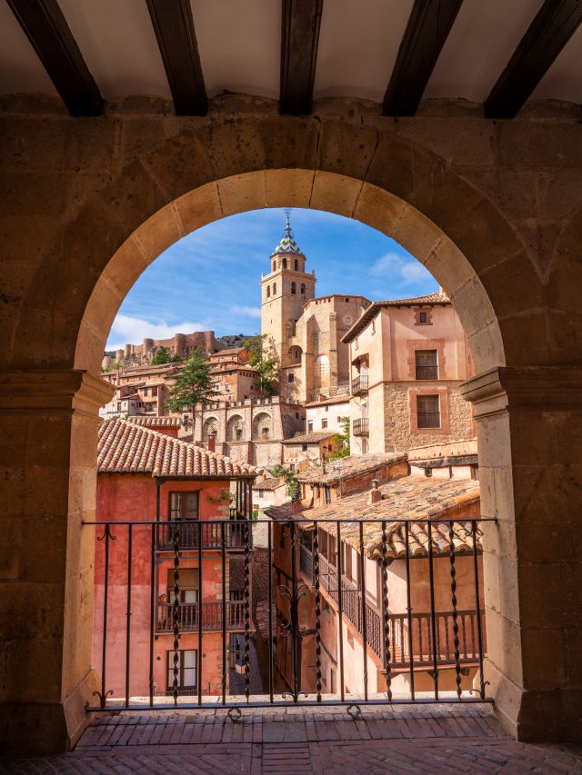 a Spanish village as seen from an old stone archway