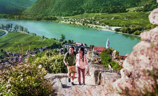 Two people hiking with the stunning view of a river behind them.